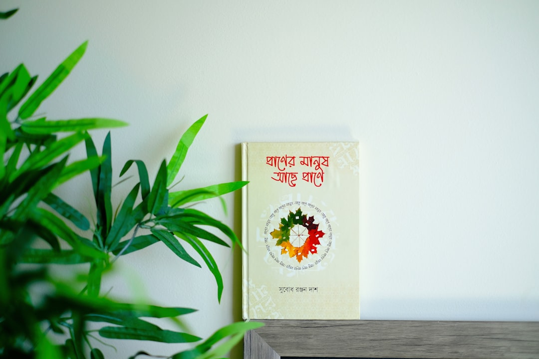 a book sitting on top of a shelf next to a potted plant