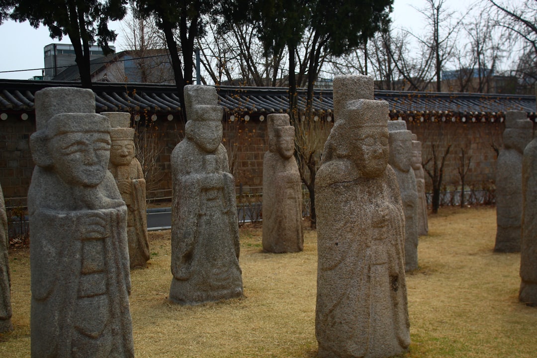 Stone statues of ancient figures stand in a grassy courtyard.